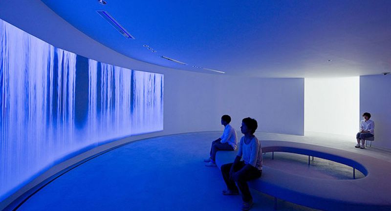 Sala de exposición de un museo con paredes curvas e iluminación azul