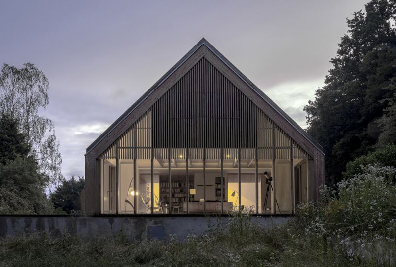 Imagen nocturna de la casa situada en el bosque obra de Java Architecture
