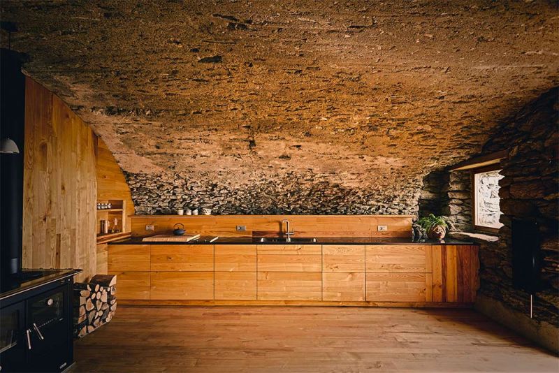 Imagen de la cocina revestida de madera de castaño y bóveda de piedra